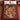 Gingerbread Icing Village woven blanket spread on a bed with a cranberry red duvet