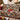 Glasshouse Poinsettia Noel Christmas woven blanket draped over a sofa by a Christmas fireplace