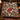 Glasshouse Poinsettia Noel Christmas woven blanket draped over a leather armchair
