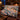 Grosbeak Hemlock Alpenglow woven blanket draped over a sofa by a stone fireplace