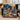 Hadestown Underworld Christmas woven blanket draped over a teal velvet sofa by a snowy window