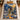 Hadestown Underworld Christmas woven blanket spread on a bed with a mustard pillow