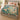 Kingfisher Waterlily Ribbons woven blanket spread across a bed in a cozy bedroom