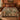 Pomegranate Vine Courtyard botanical woven blanket spread across a bed