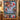 Christmas Bell Garden quilt hung on a wall with sample family name The Whitaker Family above a bench with 2 matching pillowcases